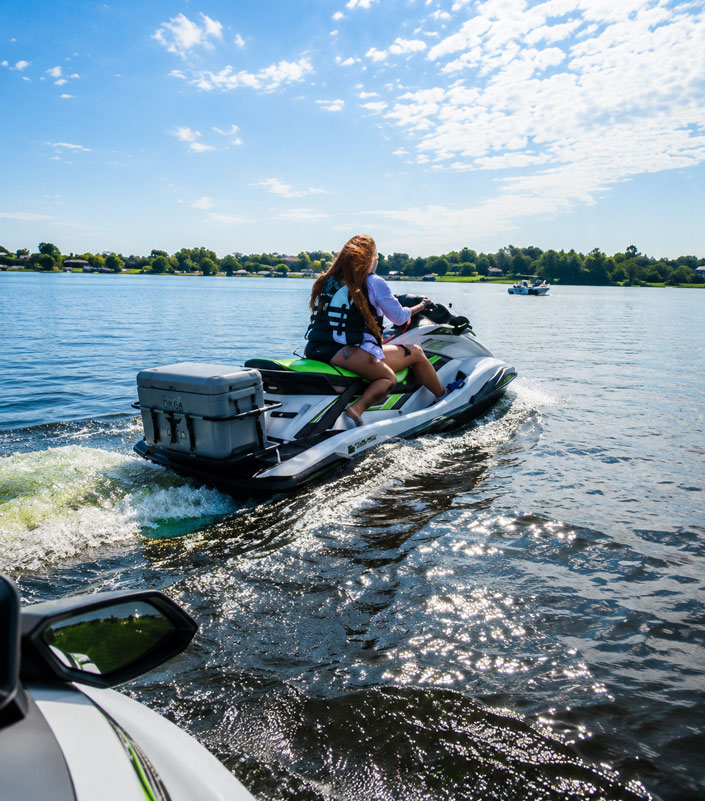Riders on Yamaha WaveRunner jet skis with Orcapak cooler rack on a lake day with a boat